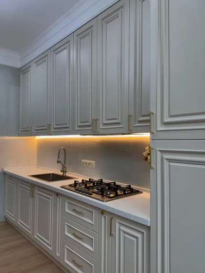 A simple and elegant kitchen with light grey moulded cabinets. The warm under-cabinet lighting provides perfect illumination for the countertop workspace.