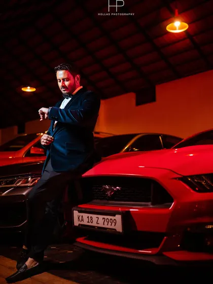 A solo portrait of the groom looking sharp at the cocktail celebration. The moody lighting and luxury cars in the background create a sophisticated and powerful image.