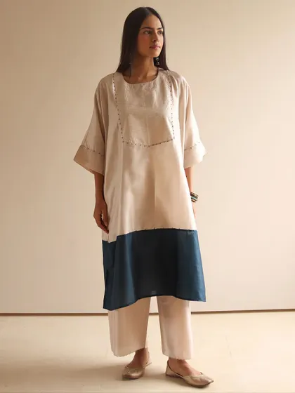 When comfort meets sophistication. This model wears a simple color-blocked tunic in beige and navy, paired with matching pants for an effortlessly chic look.