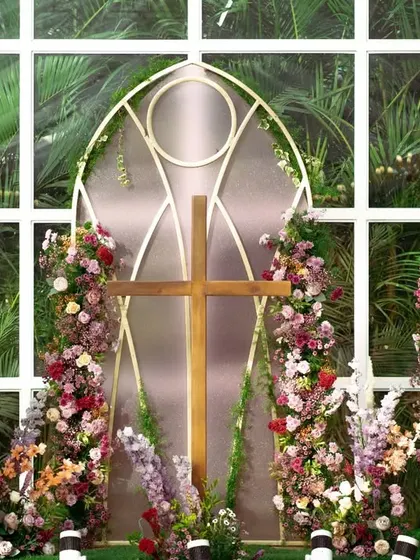 A closer view of the ceremony backdrop, designed with shapes and patterns found in classic church architecture. The floral arches add softness and color to the structure.