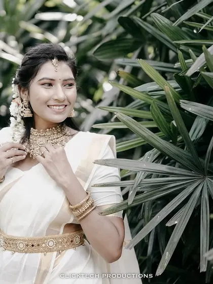 A smiling portrait of the bride-to-be in her full traditional attire, including a gold waistband (oddiyanam) and jewelry.