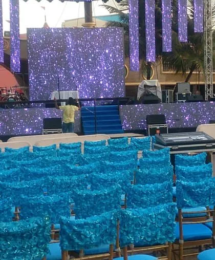 A view from the guest's perspective at the Lonavala Sangeet event. It shows the seating arrangement with decorated chairs facing the large, professionally lit stage.