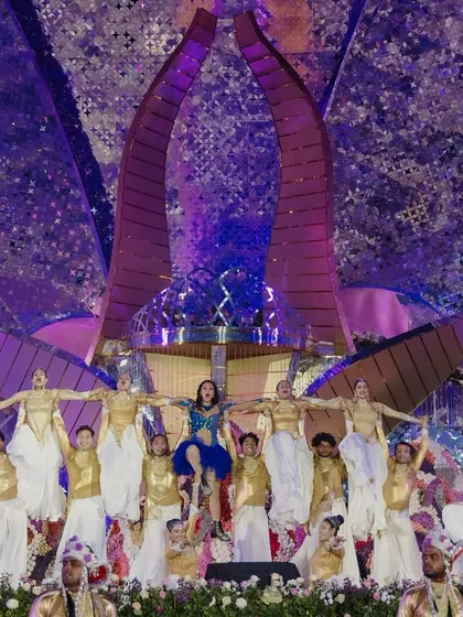 Igniting the night with a breathtaking performance. A troupe of dancers in gold and white create a stunning visual, lifting the main performer high above the stage.