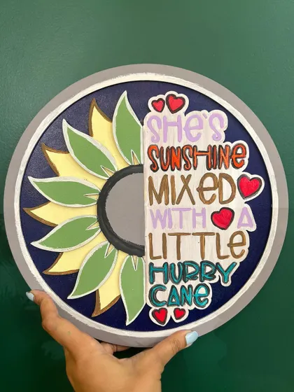A finished wall hanging with the quote "She's sunshine mixed with a little hurricane." These quote boards are a fun way to create personalized decor.
