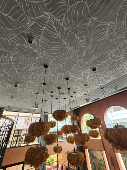 An angled view of the ceiling at The Koha, showing how the leaf patterns interact with the shadows and light from the windows and fixtures.