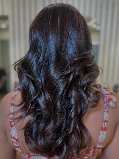 A slightly different angle showcasing the beautiful shine and texture of this dark brunette hair with subtle highlights and soft curls.