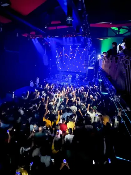 Showtime at White Lotus Club. A high-angle view shows a full house, with everyone's hands in the air, ready for a night of Bollywood and commercial hits.