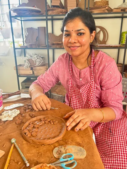 A participant fully engaged in the creative process, adding details to her hand-built clay platter.