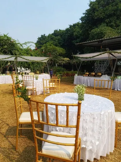 Guest seating at an elegant white-themed wedding. The tables are covered with delicate floral lace tablecloths, and the chairs are adorned with simple yet beautiful arrangements.