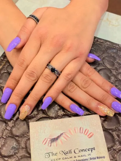 A bold set of long, square nails in a vibrant lavender color. The ring fingers are accented with a gold glitter ombre effect for a touch of warmth and sparkle.