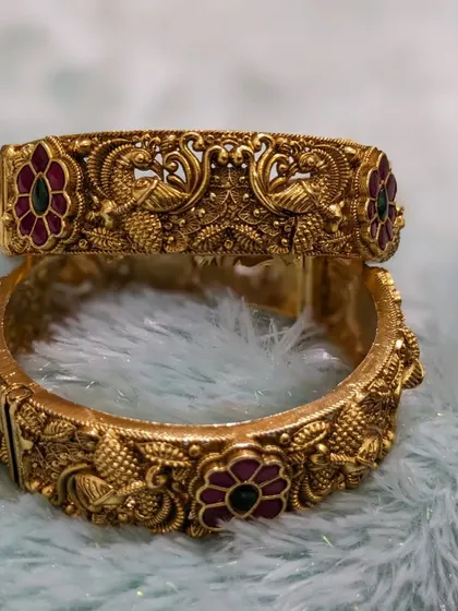 A pair of antique-finish bridal bangles (kadas) with Jadau stones and intricate peacock carvings. I offer these complimentary when you book a full bridal set!