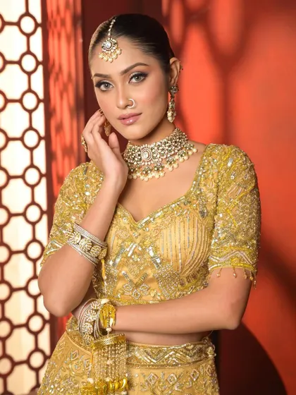 A close-up that captures the shimmering details of the golden outfit and the flawless, glowing makeup. The look is both traditional and glamorous.