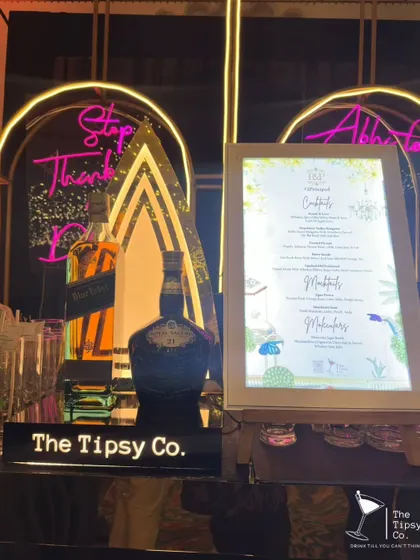 A stylish bar setup featuring top-shelf whiskies and a custom illuminated menu. The neon sign adds a modern, playful touch to the sophisticated display.
