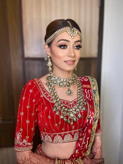 A side view showcasing the complete bridal styling. The makeup is perfectly balanced with her elaborate matha patti and layered necklaces for a regal and cohesive look.
