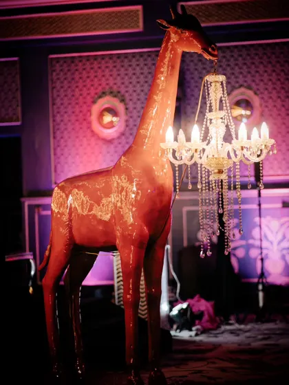 For the 'Cirque of Love' after-party, I used quirky and unexpected decor elements like this life-sized giraffe holding a crystal chandelier, adding a touch of surreal fun to the celebration.