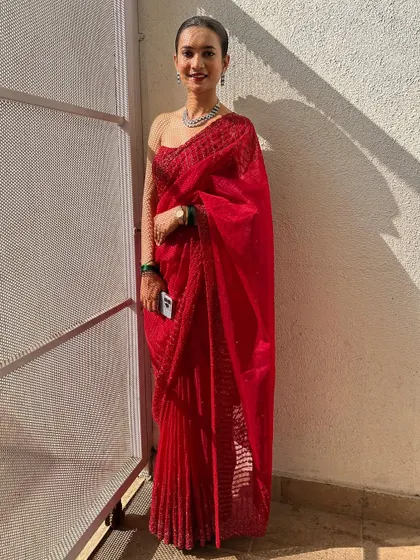 The full look of the sheer red saree. The client looks effortlessly chic and ready for her event.