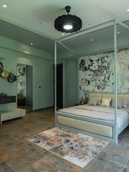 A wider view of the artistic bedroom, showing the white wardrobe and a unique bicycle-themed wall sculpture. The design balances eclectic decor with a clean, organized layout.