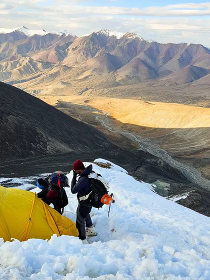 Breaking camp at high altitude on a Ladakh expedition. With the valley stretching out far below, our climbers prepare for another day of pushing their limits in this surreal landscape.