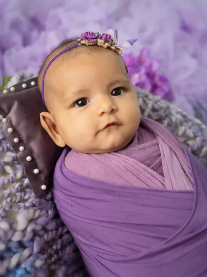 A regal portrait. This close-up shot in a purple wrap highlights the baby's beautiful eyes and serene expression.