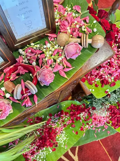 A beautiful flat lay of decor elements, including banana leaves, fresh flower petals, and wooden rattles, showcasing the theme's textures and colors.