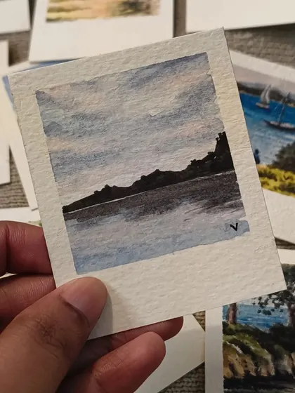 A moody and atmospheric mini painting of a silhouetted mountain range against a dusky sky, reflected in the calm water below. This piece showcases a more dramatic style of landscape art.