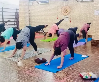 A group practicing the Downward Dog Split. This variation adds a challenge to a classic pose, working on balance and hip flexibility.