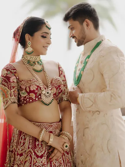 A sweet moment between the bride and groom. Her bold eye makeup and radiant skin create a stunning contrast with her partner's classic ivory sherwani.