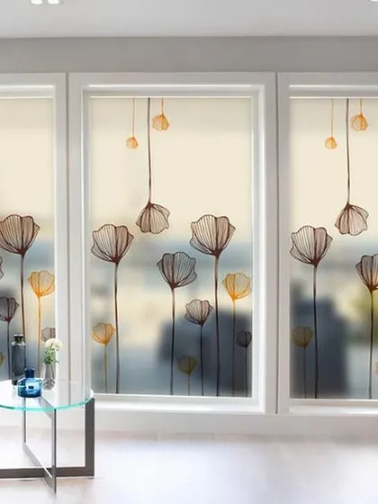 An elegant frosted film featuring stylized, dangling flowers. This pattern provides privacy for a large set of windows in a living room, creating a serene and sophisticated atmosphere.