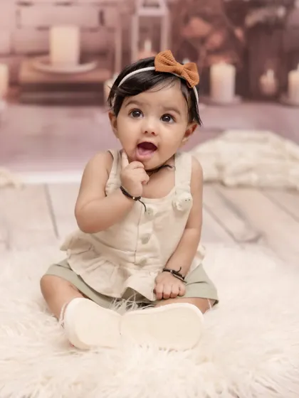 Capturing that curious and adorable sitter stage. This simple and sweet portrait of a baby girl, sitting up and exploring, focuses on her bright eyes and charming personality against a soft, neutral background.