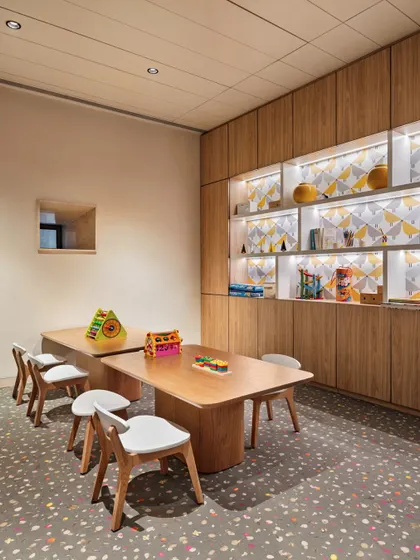 The kids' zone in the Elevate Clubhouse, a bright and playful space with light wood furniture and a colorful terrazzo floor.
