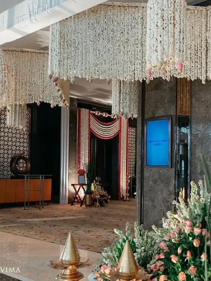 The entrance to a half-saree ceremony, adorned with fragrant jasmine garlands and banana leaves. The reflection on the polished floor doubles the beauty of this traditional South Indian decor.