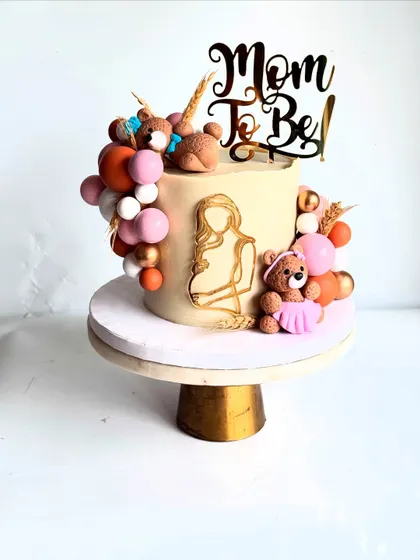 Looking for a classy and elegant baby shower cake? This design moves away from the typical pink and blue, using a sophisticated neutral palette with a 'Mom To Be' topper and cute teddy bears.