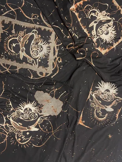 A collection of different t-shirts from a bleach art workshop, featuring celestial and whale motifs.