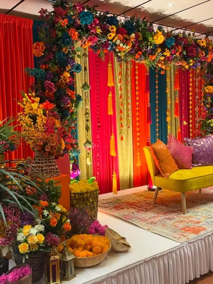 Another angle of the colorful Mehendi stage, showing the rich textures and layers of drapes and floral arrangements that create a festive atmosphere.
