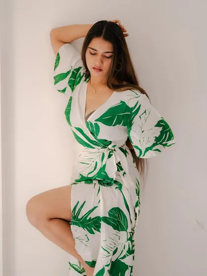 A full-length portrait of a model in a leaf-print dress on a rooftop. The composition and her pose create a stylish and summery fashion shot.