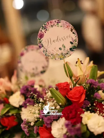 Another angle of the floral centerpiece, showing how the personalized sign is nestled within the fresh flowers. It's these small details that make our events special.
