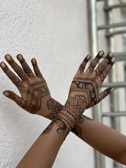 A simple crossed-arm pose showing a semi-bridal design with peacocks and traditional patterns.