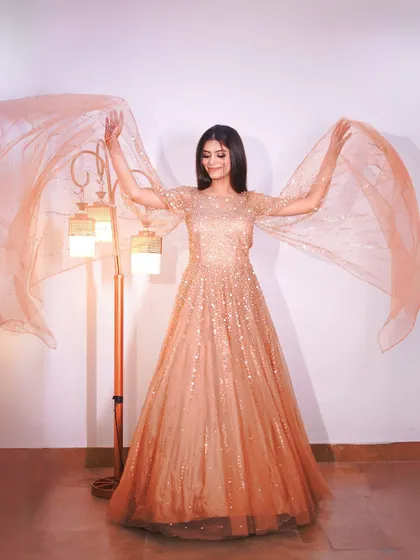 The flowing cape sleeves of the golden gown create a beautiful, dramatic effect.