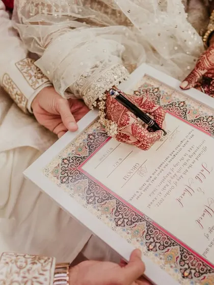 A close-up of the Nikah contract being signed, a detail shot that emphasizes the importance of the moment.