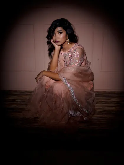 A contemplative seated pose, framed within a circle of light. This artistic choice creates a sense of intimacy and draws the viewer's eye directly to the model and her elegant outfit.