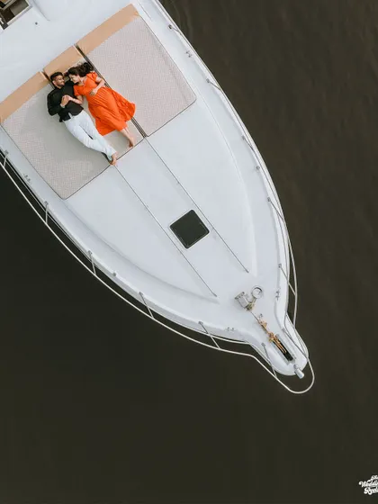 An aerial drone shot of a couple relaxing on a private yacht in Goa. This highlights my experience with destination pre-wedding shoots and creating unique, aspirational images.