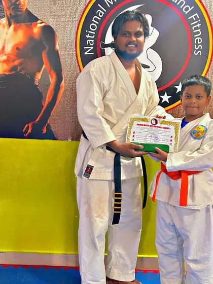 Another student proudly accepts his orange belt after a successful Karate grading.