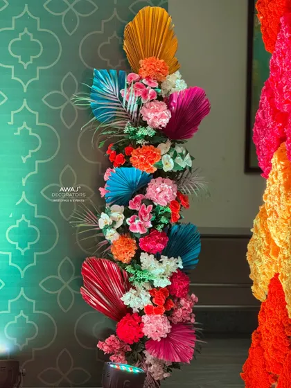 A stunning floral arrangement for a Mehendi, featuring a rainbow of colors and exotic palm leaves.