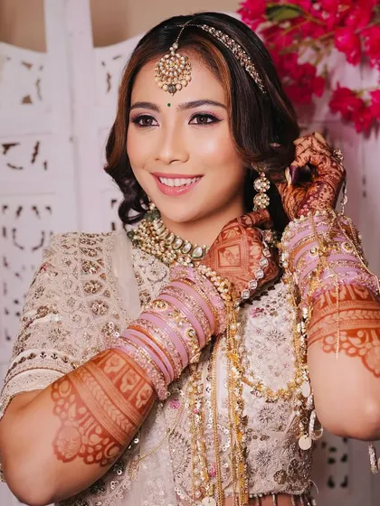 A close-up of the bride's hands, showing her intricate henna and the beautiful detailing on her ivory rental lehenga.