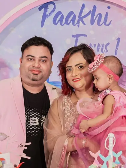 A sweet family photo in front of a pastel mermaid-themed backdrop for a first birthday celebration.