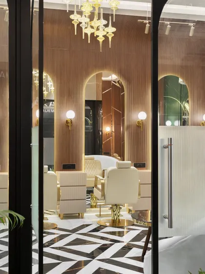 A view into the makeup studio from the entrance, showcasing the fluted wood panels, arched mirrors, and a stunning glass chandelier that sets a tone of luxury from the moment you walk in.
