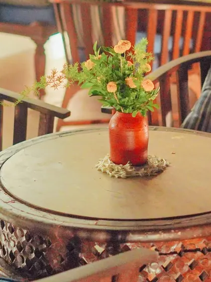 Even the simplest elements can elevate a space. A small, rustic vase with a few fresh flowers on a carved wooden table helps tie a seating area into the main event decor, ensuring a cohesive look throughout the home.
