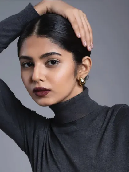 A powerful and sophisticated look featuring a bold, dark lip and a clean, low bun. This is a great example of a simple but high-impact makeup and hair combination.