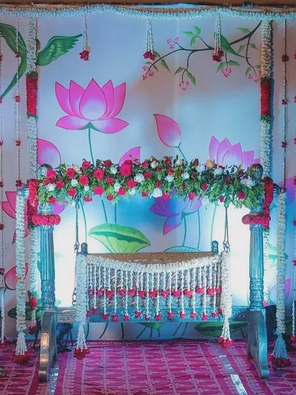 A classic naming ceremony with a lotus-themed backdrop and a traditional silver cradle. The combination of the printed backdrop and real flower garlands creates a beautiful layered effect.