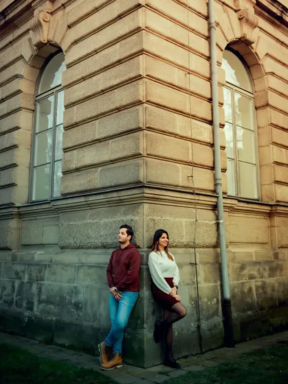 A stylishly posed shot of a couple on the corner of a historic building. Their poses create a sense of balance and connection, blending modern love with timeless architecture.